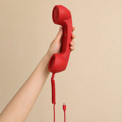 The red DialBop Retro Handset held in one hand, for scale, cord and USB-C plug hanging below