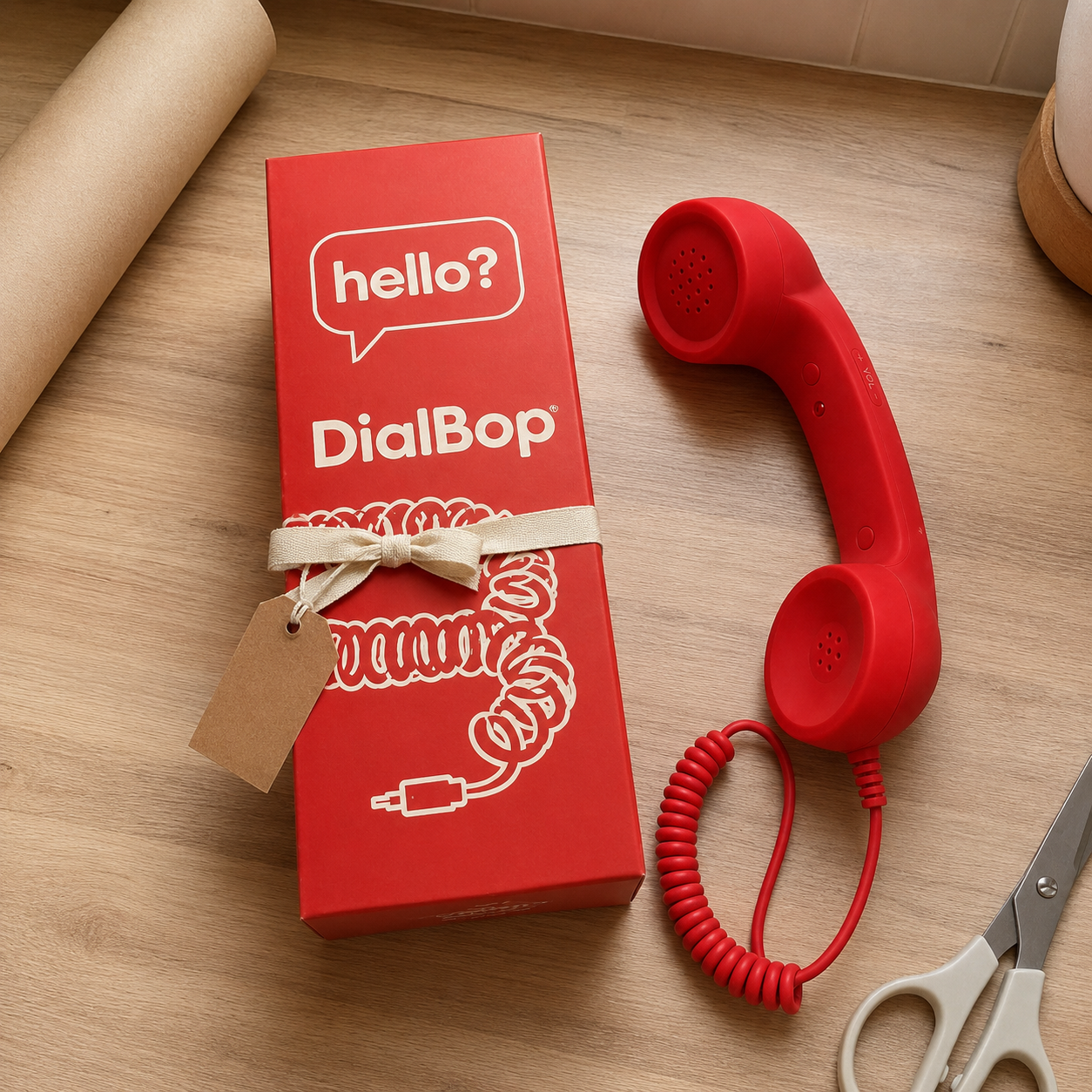 The red DialBop box tied with a cream ribbon and a blank gift tag, the handset beside it on a kitchen counter